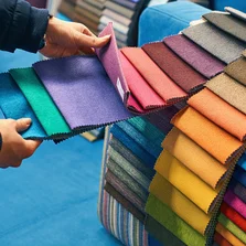 Fantastisch große Auswahl an Farben, Strukturen & Mustern - In einem Geschäft wählt eine Frau einen Stoff in einer passenden Farbe aus einer Vielfalt von Musterlaschen für Ihren Sonnenschutz.